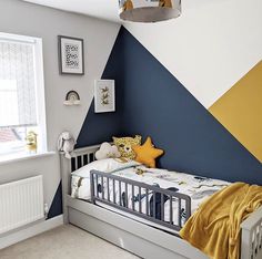 a child's room with a bed and wall painted in blue, yellow and white