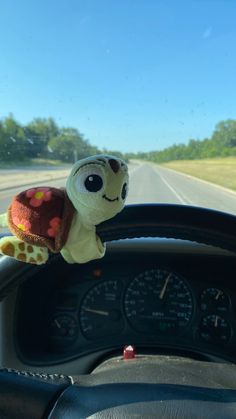 a stuffed turtle sitting on the dashboard of a car