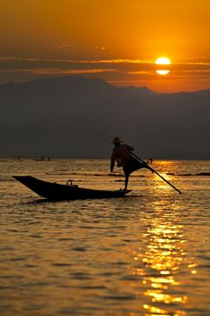 a person rowing a boat in the water at sunset