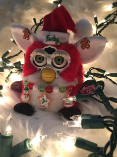 a stuffed animal wearing a santa hat on top of a white christmas tree with lights