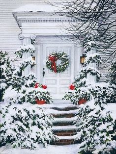 a white house covered in snow with wreaths on the front door and steps leading up to it