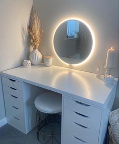 a white vanity with a round mirror and lights on it's sides, next to a stool