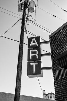 a black and white photo of an art sign on the side of a building next to a traffic light