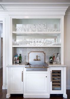 a kitchen with white cabinets and glassware on the shelves