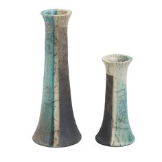 two tall vases sitting next to each other on a white surface with blue and grey stripes