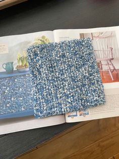 an open magazine on a table with a blue and white rug next to the book