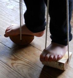 a person standing on top of a piece of wood with ropes attached to the feet