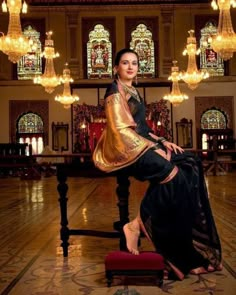 a woman sitting on top of a bench in a room with chandeliers hanging from the ceiling