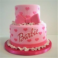 a pink cake with hearts and bows on it's sides that says barbie written on the side