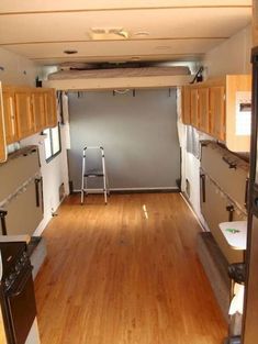 the inside of an rv with wood floors and white appliances on each side of the door