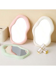 three different shaped mirrors sitting on top of a counter next to toilet paper and other items