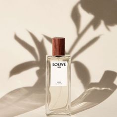 a bottle of loewe perfume sitting on a table next to a shadow of a plant