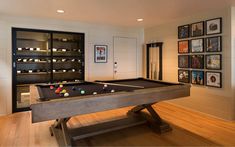 a pool table in the middle of a living room with pictures on the wall behind it