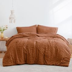 a bed with a brown comforter on top of it in a room next to a table