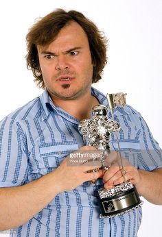 a man holding an award in one hand and making a surprised face on the other