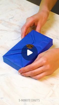 a person is opening a blue box with a piece of paper in it on a table