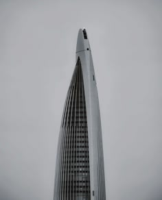 a very tall building with a clock on it's side in the foggy sky