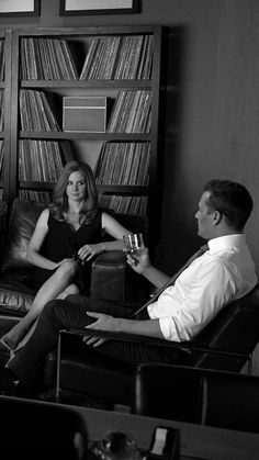 black and white photograph of two people sitting on couches in front of bookshelves