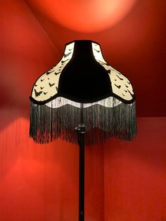 a lamp that is sitting on top of a stand in front of a red wall