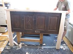 a man standing next to a wooden cabinet