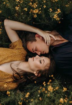 a man and woman laying in the grass next to each other with their eyes closed