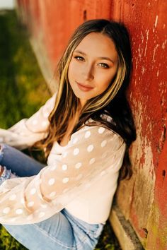 a young woman sitting against a red wall