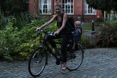 a woman riding a bike with a child on the back