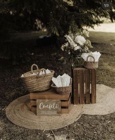 two baskets with flowers and napkins sit on a rug in front of a tree