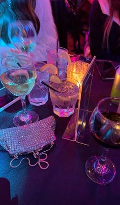 there are many glasses on the table and one is filled with water, wine or liquor