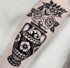 a black and white tattoo with flowers in a vase on the right arm, by person