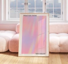 a pink and blue poster sitting on top of a wooden floor next to a window