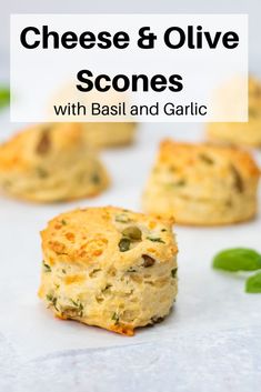 cheesy and olive scones with basil and garlic on a white surface next to green leaves