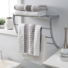 a towel rack with towels hanging on it in a bathroom next to a bathtub