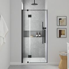 a bathroom with a glass shower door and white tile flooring, along with pictures on the wall