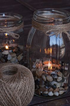 three mason jars filled with rocks and lit candles