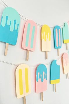 popsicles with ice cream on them are hanging from a string in front of a white wall