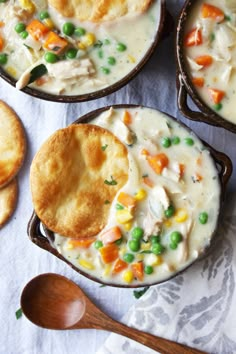 four bowls filled with chicken pot pies next to crackers on a white tablecloth