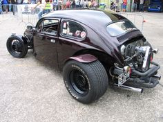 an old fashioned car is parked on the street with people standing around and looking at it