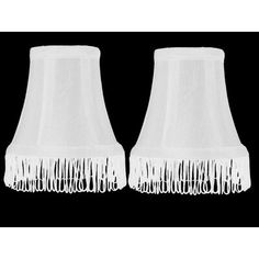 two white lamps with fringes on them