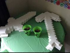 two green buckets filled with crayons sitting on top of a table covered in white paper