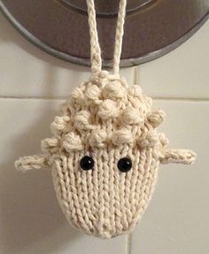 a crocheted sheep hanging from a hook on a bathroom wall with white tiles