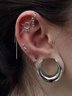 a woman's ear with three different piercings on the top and one behind her ear