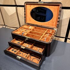 an open wooden box with jewelry inside on a table