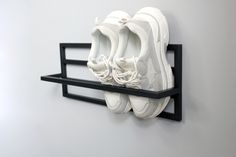 there are three pairs of shoes hanging on the wall with one pair in it's shoe rack