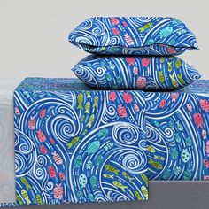 three pillows are stacked on top of each other in front of a white wall with blue and pink designs