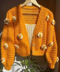 an orange knitted jacket with white flowers on it