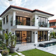 a large white house with lots of windows and doors on the front of it, next to a swimming pool