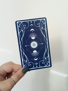 a hand holding up a playing card with an eye on it's front side