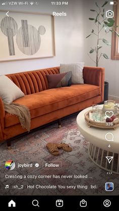 an orange couch sitting in a living room next to a white coffee table and potted plant