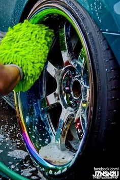 a person washing a car wheel with a green rag